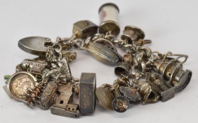 Lot 1555 - A silver charm bracelet with twenty-six...
