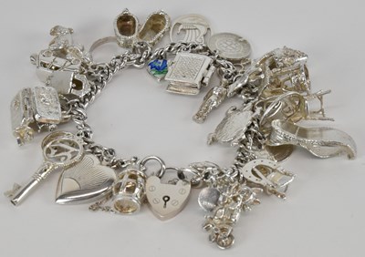 Lot 1464 - A silver charm bracelet, with twenty-seven...