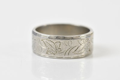 Lot 1393 - A platinum wedding band with chased floral...