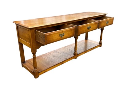 Lot 35 - A reproduction oak three drawer dresser base,...