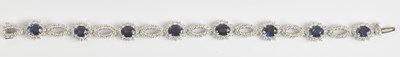 Lot 1340 - An 18ct white gold diamond and sapphire line...