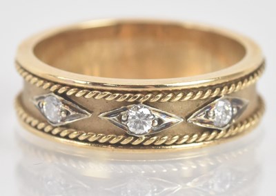 Lot 1296 - A 9ct yellow gold three stone diamond set band...