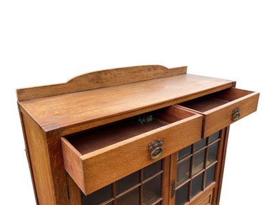 Lot 11 - An Arts and Crafts light oak bookcase with...