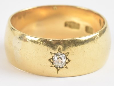 Lot 1244 - An 18ct gold band ring with central set...