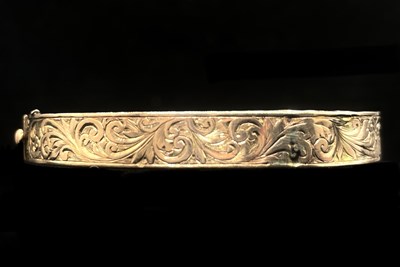 Lot 1111 - A 9ct rose gold hinged oval bangle with...