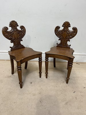 Lot 1200 - A pair of Regency style carved oak hall chairs...