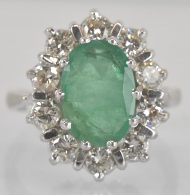 Lot 1103 - An 18ct white gold diamond and emerald ring,...