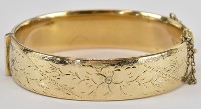 Lot 1317 - A 9ct gold metal core hinged bangle, the front...
