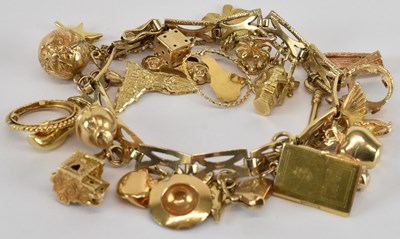 Lot 1295 - A 9ct gold charm bracelet, with twenty-six...