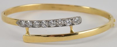 Lot 1297 - An 18ct gold hinged bracelet, the crossover...