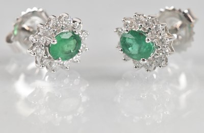 Lot 1240 - A pair of 18ct white gold emerald and diamond...