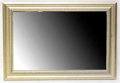 Lot 115 - A rectangular wall mirror with silver-coloured...