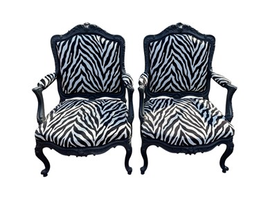 Lot 2078 - A pair of ebonised open sided elbow chairs,...