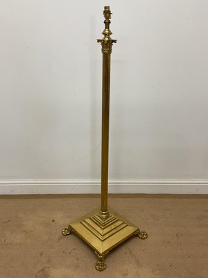 Lot 664 - A brass column floor lamp on raised claw feet...