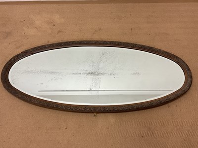 Lot 747 - A carved oak framed oval wall mirror with...