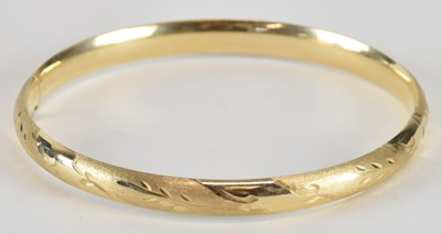 Lot 1609 - A 14K yellow gold hinged bangle with cut...