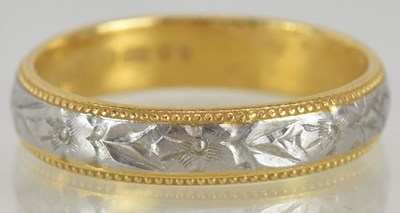 Lot 1246 - A 22ct yellow and white gold wedding band,...