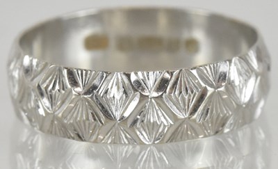 Lot 1251 - An 18ct white gold wedding band, with textured...