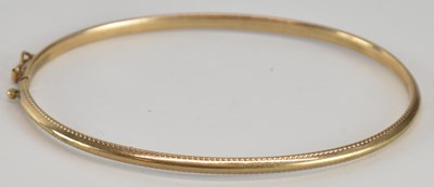 Lot 1621 - A 9ct gold rigid bracelet, with beaded pattern...