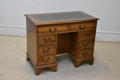 Lot 2104 - A reproduction kneehole nine drawer desk, with...