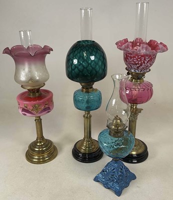 Lot 659 - Four brass oil lamps, two on porcelain plinths,...