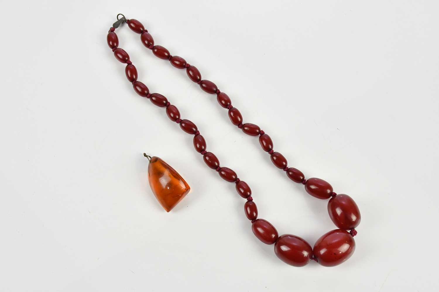 Lot 9 - A graduated cherry amber coloured necklace and...