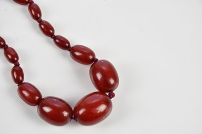 Lot 9 - A graduated cherry amber coloured necklace and...