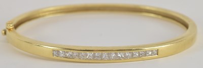 Lot 1571 - An 18ct hinged oval bracelet, with channel set...