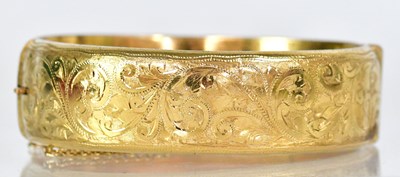 Lot 808 - A 9ct gold bangle, half engraved with scroll...