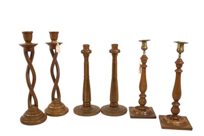 Lot 1039 - Three pairs of turned wooden candlesticks, one...