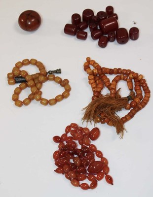 Lot 1197 - A group of amber coloured beads, one large...
