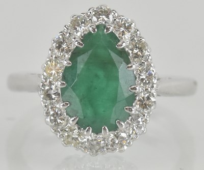 Lot 1151 - An 18ct white gold emerald and diamond cluster...