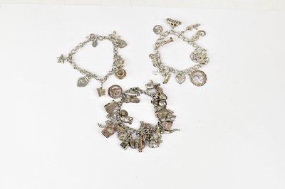 Lot 1054 - Three silver charm bracelets all with various...