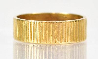 Lot 1011 - An 18ct yellow gold textured wedding band,...