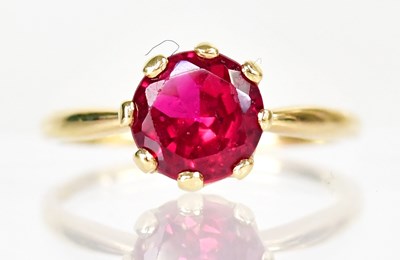 Lot 1017 - An 18ct yellow gold dress ring set with a red...