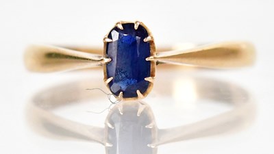 Lot 1274 - An 18ct yellow gold ring set with a blue stone,...
