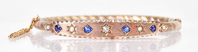 Lot 1050 - An Edwardian yellow metal hinged bangle, set...