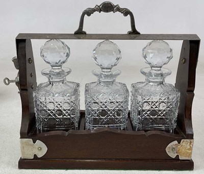 Lot 423 - A silver plate mounted three bottle tantalus,...