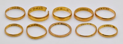 Lot 1068 - Ten 22ct gold wedding bands (one cut),...