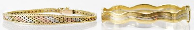 Lot 1083 - A 9ct yellow and white gold hinged wavy bangle,...