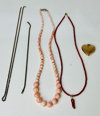 Lot 653 - A graduated string of coral coloured beads, a...