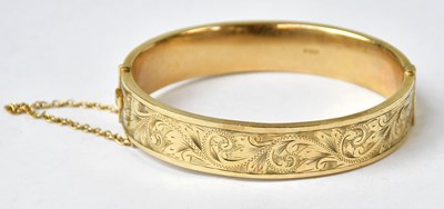 Lot 1060 - A 9ct yellow gold bangle with engraved foliate...