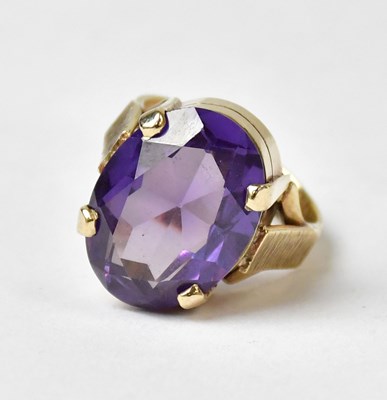Lot 1025 - A 9ct yellow gold ring set with an oval purple...