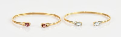 Lot 1191 - A 9ct yellow gold bangle set with two oval cut...