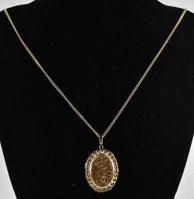 Lot 1377 - A 9ct yellow gold oval locket, with floral...