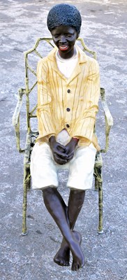 Lot 93 - A decorative composition figure of a seated boy