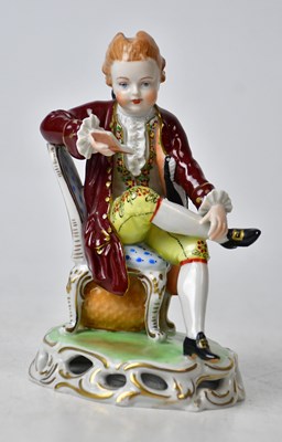 Lot 141 - DRESDEN; a porcelain figure of a boy seated on...