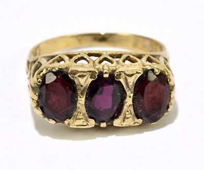 Lot 1059 - A 9ct yellow gold and garnet three stone ring,...