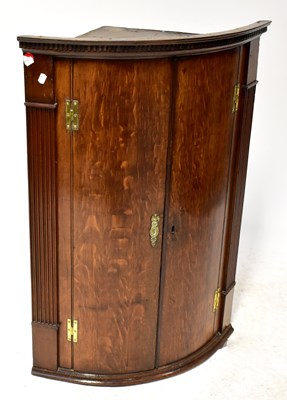 Lot 88 - A Georgian oak bow-fronted corner cupboard...