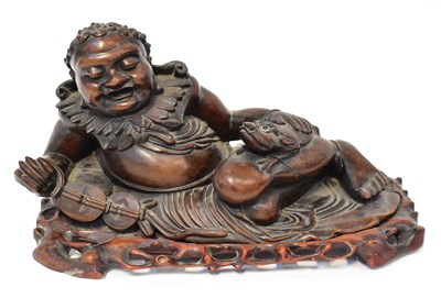 Lot 216 - A carved figure group of a recumbent Buddha...